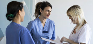 Tre kvinnor som diskuterar i sjukhusmiljö
